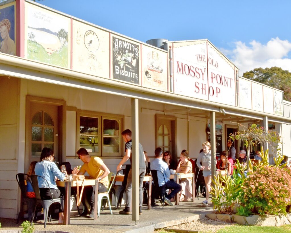 A single level general store has been converted into a cafe, surrounded by gardens and outdoor dining.