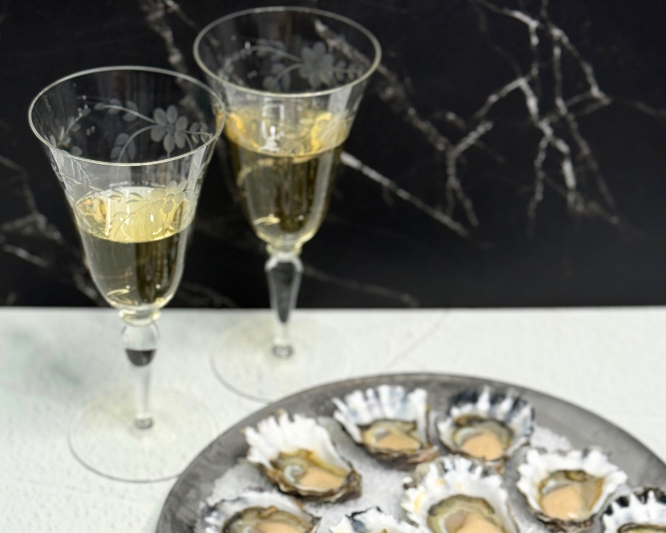 A plate of Rock Oysters with 2 glasses of champagne in the background
